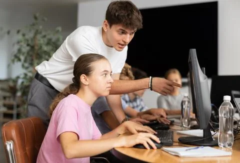 Preteen girl learning computer programs with teacher in training room Fotos de archivo