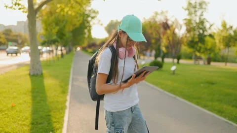 Preteen using digital tablet while walking outdoors on a sunny day. Stock Footage 340924662