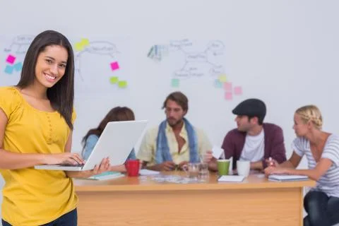 Prettty editor using laptop as team works behind her Stock Photos
