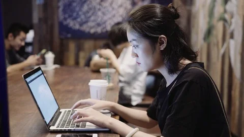 Pretty Asian girl on her computer working in a coffee shop Stock Footage 81457736
