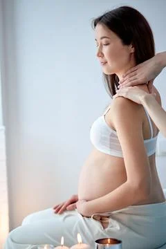 Pretty asian pregnant female getting spa massage on back, hugging tummy Stock Photos