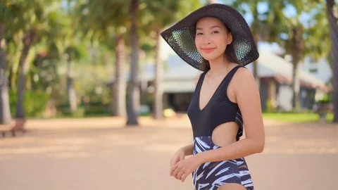 A pretty Asian woman in her bathing suit moves in the frame as she adjusts Stock Footage 122517841