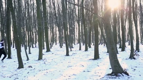 Pretty athletic guy running in the winter in the woods and listening to music Stockbeeldmateriaal 77070171
