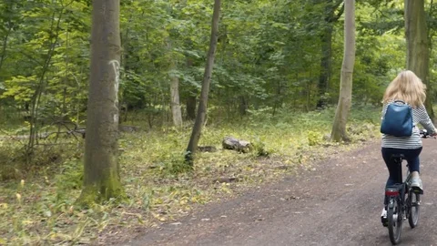 Pretty Blonde with a backpack on a bicycle in a summer park Stock-Footage 78589173