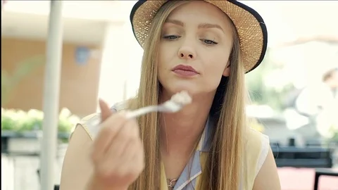 Pretty, blonde girl eating tasty dessert and looks happy, steadycam shot Stock Footage