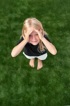 Pretty blonde girl looking at camera, standing on green grass. Mock up black t Stock Photos