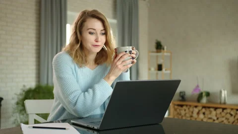 Pretty blonde having conversation via video link on laptop at home. Timelapse Stock Footage 237944499