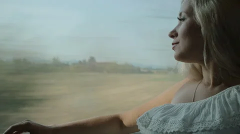 Pretty blonde looks through the window of the moving train Stock Footage 59802916