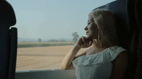 Pretty blonde looks through the window of the moving train Stock Footage 59803119