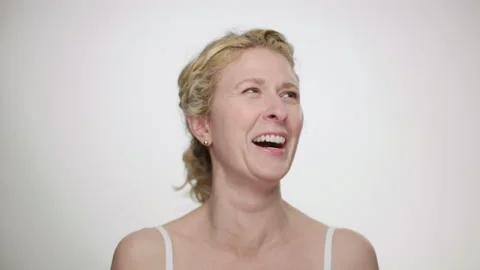 Pretty blonde model laughs in response to someone's joke off camera slow motion Stockbeeldmateriaal 193818044