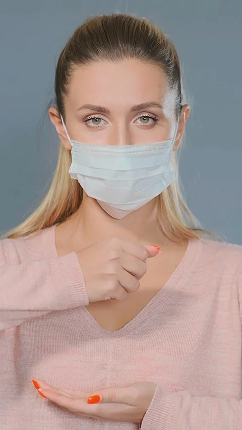Pretty blonde in pullover and face mask throws pills on palm Stockbeeldmateriaal 127953181