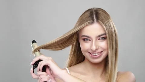 Pretty blonde using curling iron and smiling Stock Footage 146598391