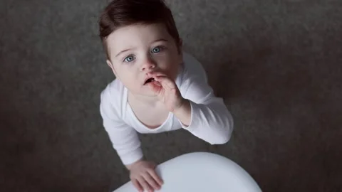 Pretty boy on a gray background. He points his fingers of hand on his teeth and Video stock 153839782