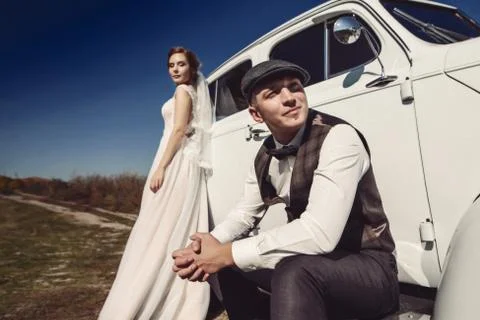 Pretty bride and handsome groom in the retro car Stock Photos