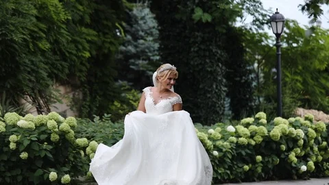 Pretty bride in long white wedding dress runs near fiance Stock Footage 113672958