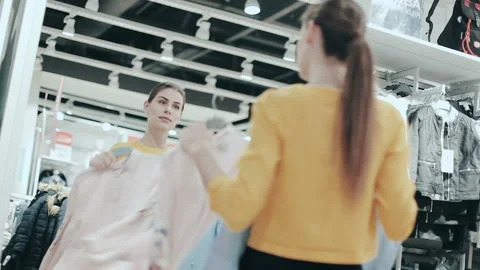 Pretty brunette choosing between two blouses. Young smiling woman checking Video stock 85753617