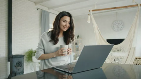 Pretty brunette communicates via video link on laptop sitting at table in room Stock-Footage 244326128