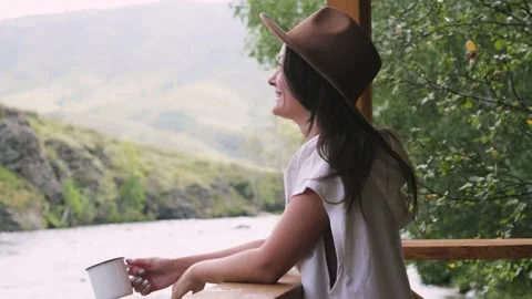 Pretty brunette in a hat and white sweater makes spray out of a mug. happy girl Vidéo 131140306