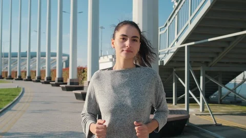 Pretty brunette lady is jogging alone outdoors, frontal view on face Stock Footage 111158342