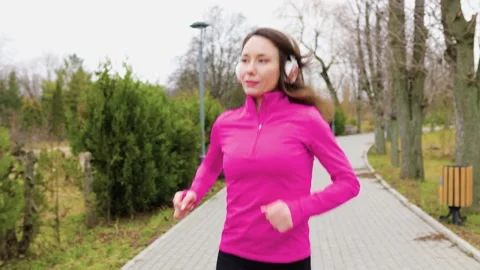 A pretty brunette runner jogging along a parkway Stock Footage 234137134