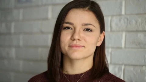 Pretty brunette standing next to the brick wall and smiling to the camera Stock Footage 73497532