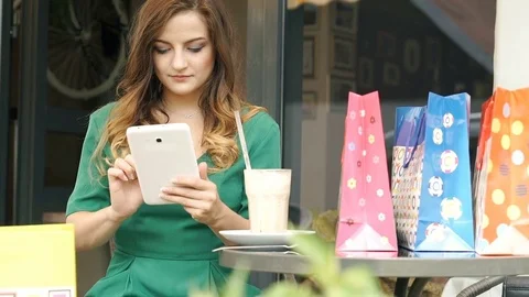 Pretty brunette using tablet in the outdoor cafe and smiling to the camera, stea Vídeo Stock 79391033