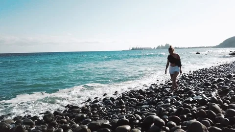 Pretty brunette is walking around the beach, enjoying blue ocean and turquoise Stock Footage 94125830