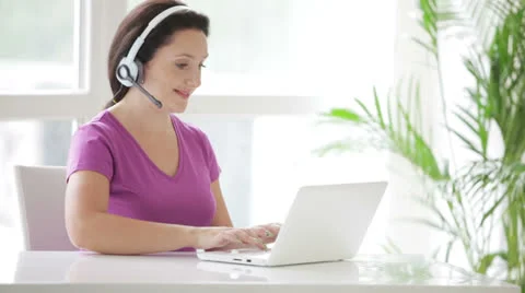 Pretty call centre operator in headset at work using laptop Video stock 26003553