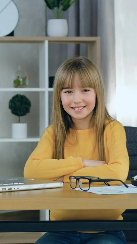 Pretty cheerful modern smart 10-aged girl in casual clothes poses on camera with Stock Footage 332731924