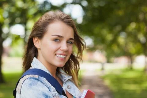 Pretty cheerful student holding folder and notebook Stock Photos