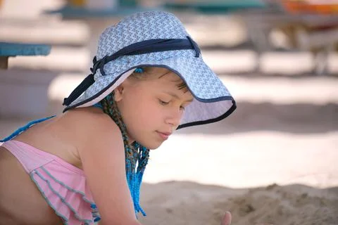 Pretty preteen girl in bikini swimsuit playing with sand in