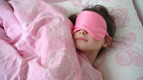 Pretty child sleeping in her bed with pink eye sleeping mask  Stock Footage 152097227