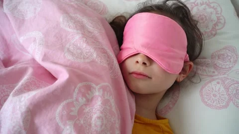 Pretty child sleeping in her bed with pink eye sleeping mask  Stock Footage 152097254