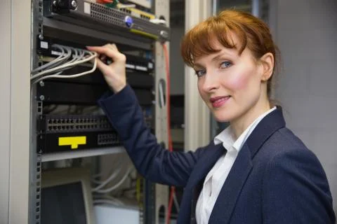 Pretty computer technician smiling at camera while fixing server Stock Photos
