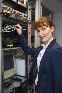 Pretty computer technician smiling at camera while fixing server Stock Photos