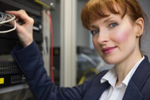 Pretty computer technician smiling at camera while fixing server Stock Photos
