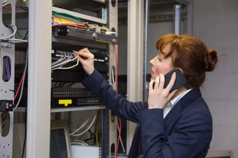 Pretty computer technician talking on phone while fixing server Stock Photos