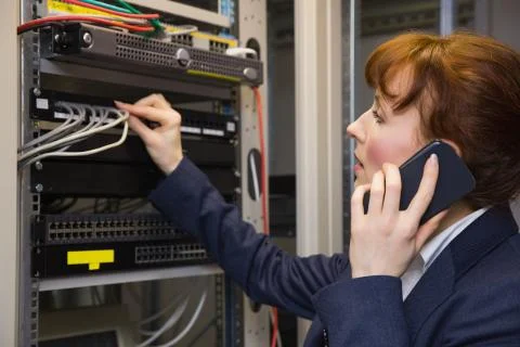 Pretty computer technician talking on phone while fixing server Stock Photos