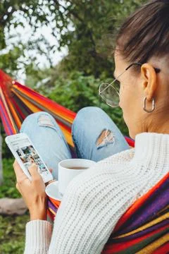 Pretty content creator in hammock use smartphone look at screen chat in socia Stock Photos