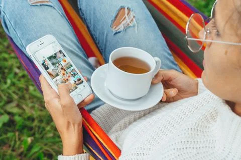 Pretty content creator in hammock use smartphone look at screen chat in socia Stock Photos
