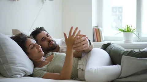 Pretty couple in bed talking and touching hands relaxed Spbd. girlfriend and Video stock 128284549