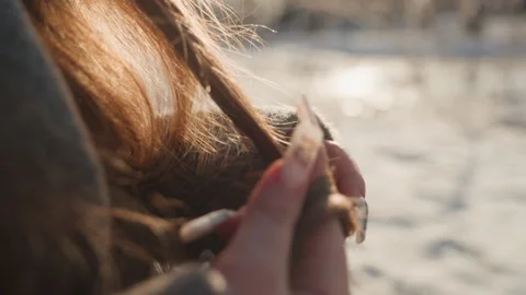 Pretty curl glowing in winter sun, fingers brushing hair end over snowy Stock Footage 342431316