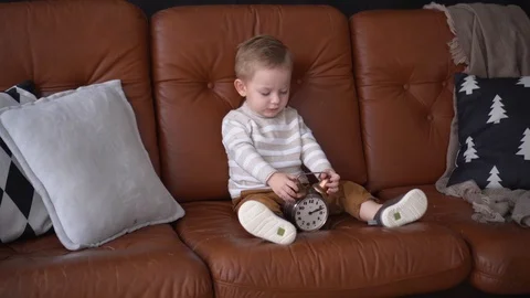 Pretty cute small boy is sitting alone on sofa, posing at home. Video stock 120541252
