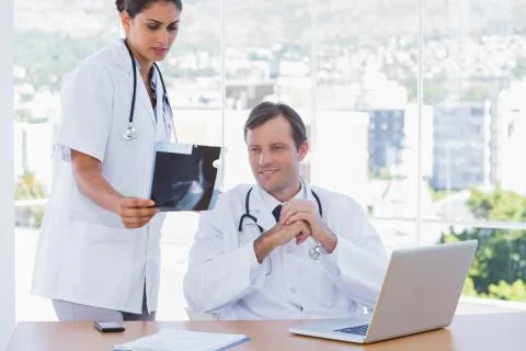 Pretty doctor showing a x ray to a colleague Stock Photos