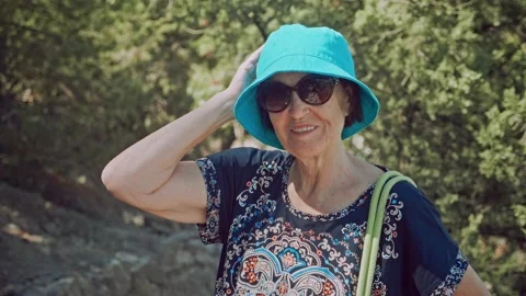 Pretty elderly lady standing on hiking trail, looking at the camera and smiling 動画素材 196297909