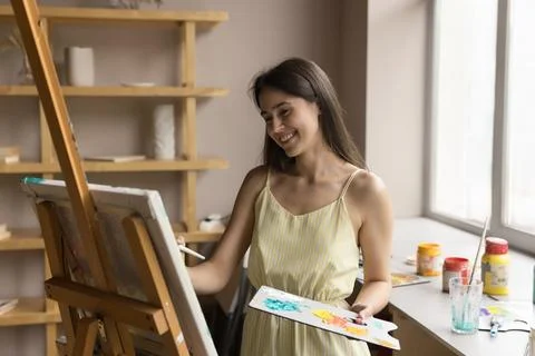 Pretty female artist create pictures, painting on canvas with paints Stock Photos