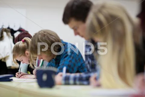 Pretty female college student sitting in a classroom full of stu Stock Photos