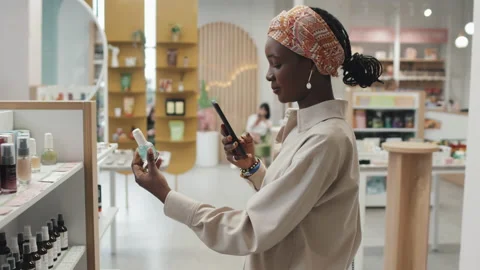 Pretty Female Consumer Scanning Codes on Bottles with Cosemtic Products Vidéo 223512811