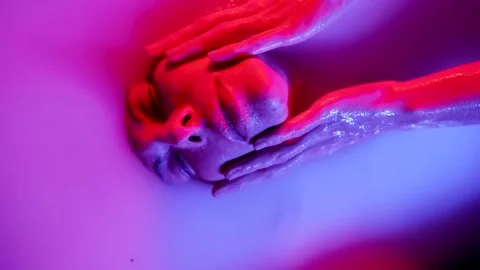 A pretty female face with lips pumped up by a filler plunges into a bath with a Stock Footage 232501636