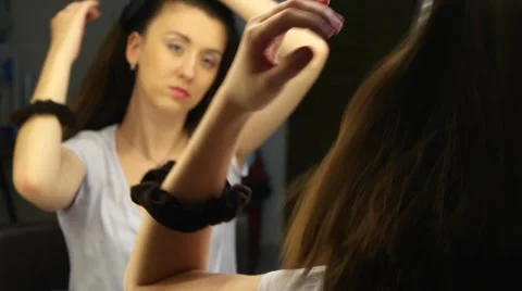 Pretty female model combing her hair in front of mirror Stock Footage 62472886
